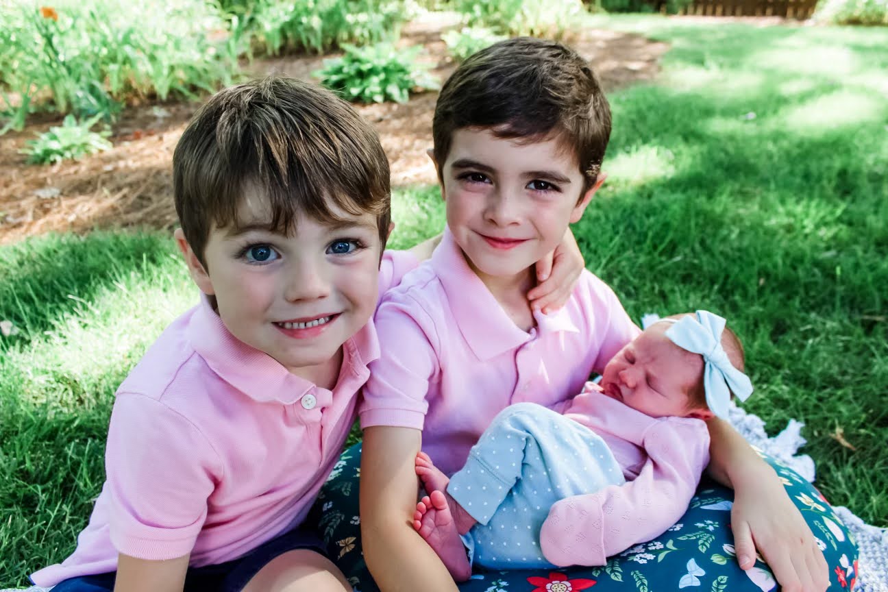 Newborn Lizzie being held with her brothers nearby